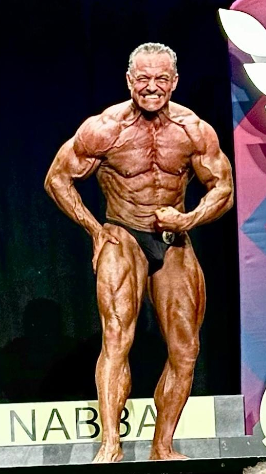 Carlo on stage in 2023, winning the NABBA Masters over 55 category